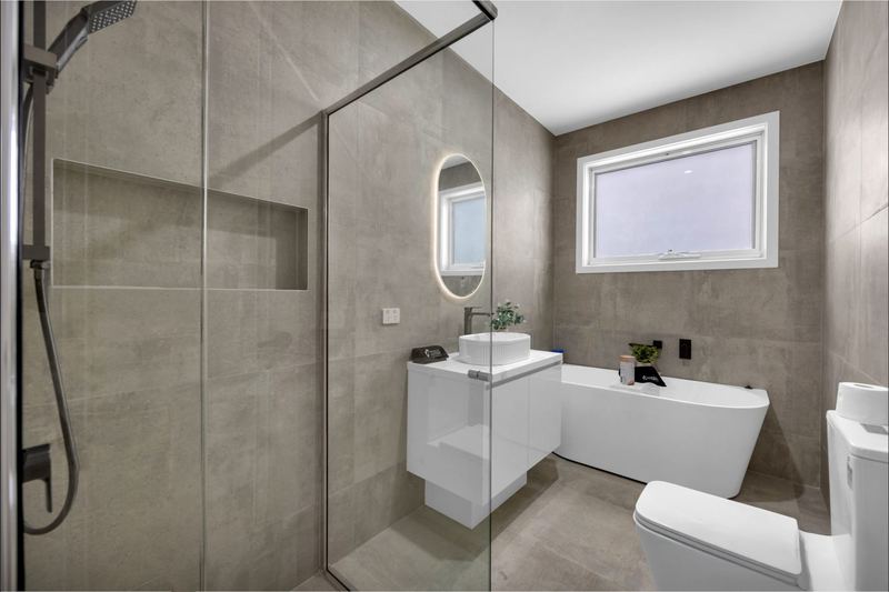 Main bathroom with freestanding bath, shower niche and floor-to-ceiling tiles