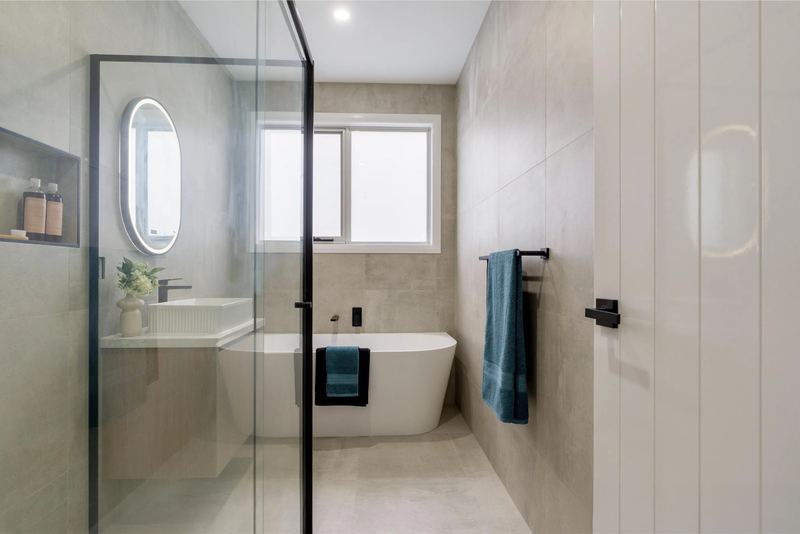 Main bathroom with freestanding bath and floor-to-ceiling tiles
